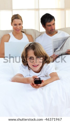 Joyful child holding a remote lying in the bed