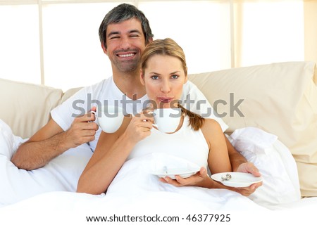 Intimate couple drinking coffee lying in the bed at home