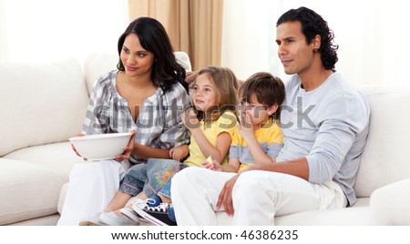 Smiling family watching TV on sofa in the living room