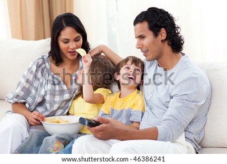 Merry family watching TV on sofa in the living room
