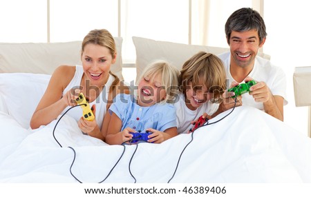 Adorable family playing video game lying on bed