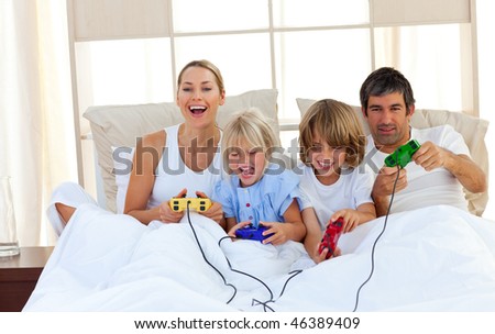 Loving family playing video game lying on bed
