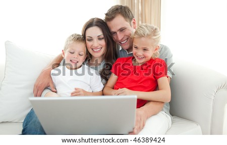 Joyful family using a computer sitting on sofa in the living room