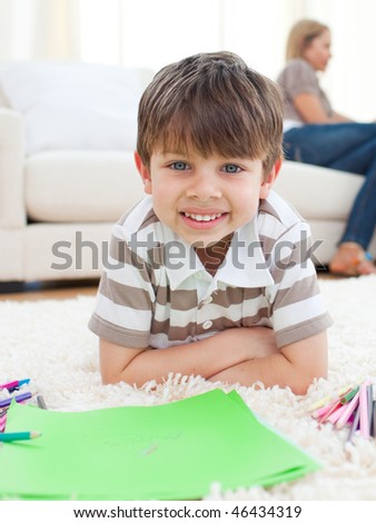 Portrait of little boy drawing lying on the floor in the living room