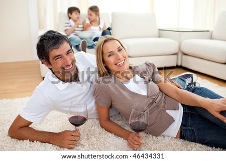 Affectionate lovers drinking wine lying on the floor in the living room