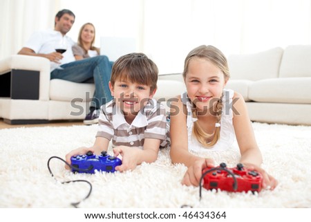 Brother and sister playing video games lying on the floor