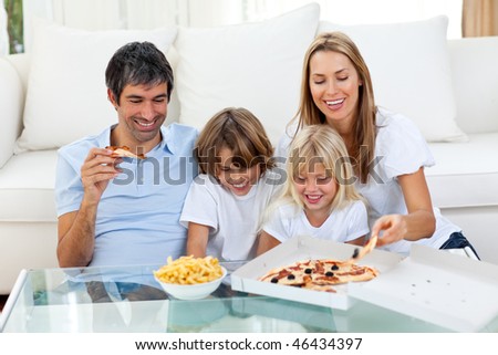 Positive family eating pizzas sitting on sofa