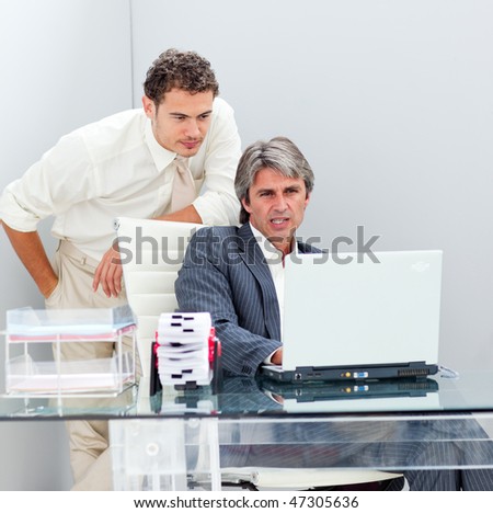 Confident manager helping his colleague work at a computer in the office