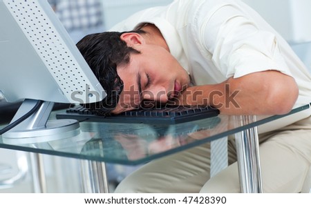 Tired businessman sleeping at his desk in the office