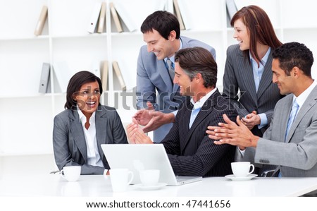Laughing businesswoman applauded by her team in the office