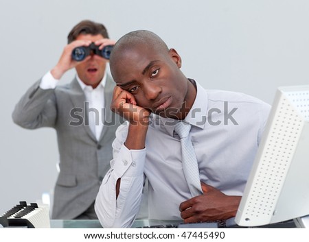 Ethnic businessman getting bored and his manager looking through binoculars in the office