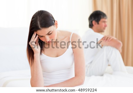 Upset couple sitting sitting separately on their bed after having a row