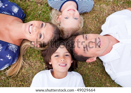 Cheerful family lying in circle on the grass in a park