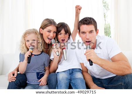 Portrait of a lively family singing through microphone in the living room