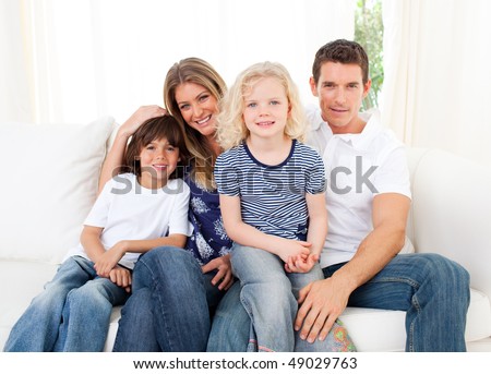 Joyful family watching television sitting on sofa at home