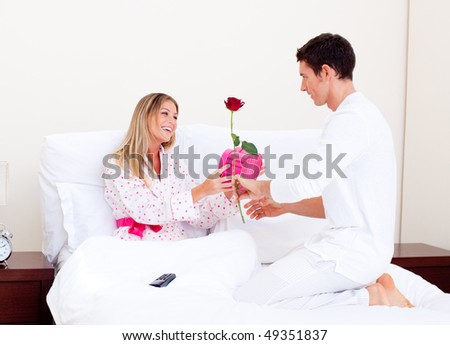 Adorable husband giving a present to his wife in the bedroom