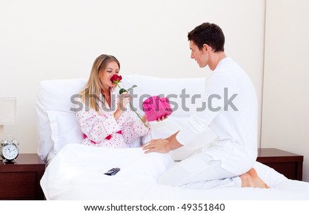 Handsome husband giving a present to his wife in the bedroom