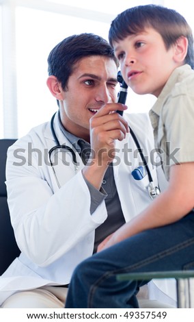 Charismatic doctor examining little boy\'s ears at the practice