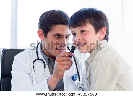 Serious doctor examining little boy\'s ears at the practice
