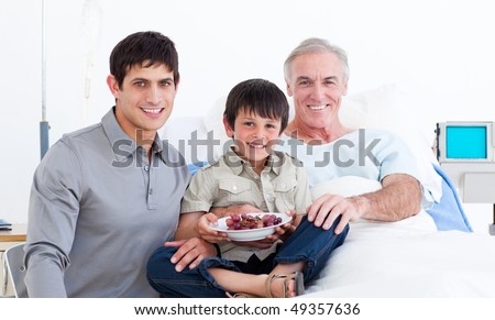 Smiling father and son visiting grandfather at the hospital