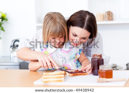 Affectionate mother helping her daughter prepare the breakfast in the kitchen