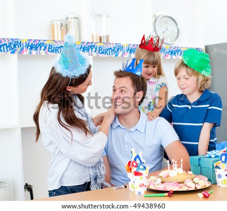 Elated man celebrating his birthday with his wife and his children in the kitchen