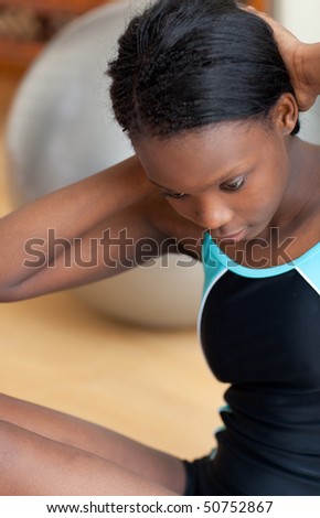 Attractive woman in gym outfit doing sit-ups at home