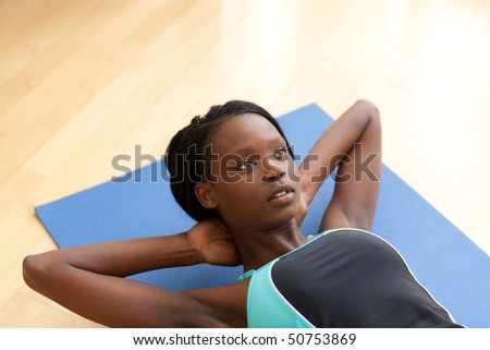Charming woman in gym clothes doing sit-ups at home
