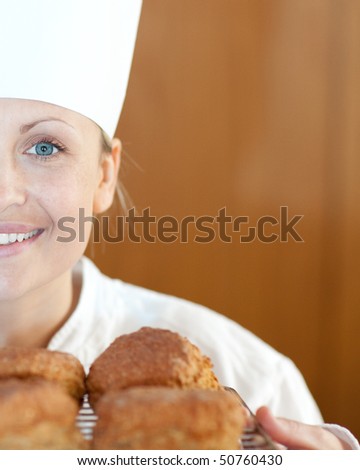 Close-up of a smiling female chef baking scones in the kitchen