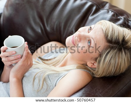 Charming woman drinking coffee sitting on a sofa in a living-room