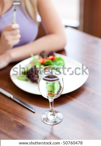 Close-up of a young woman eating a salad in a living-room