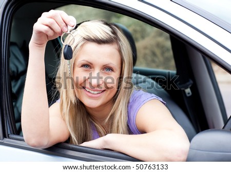 Female driver showing a key with a thumb up after buying a new car