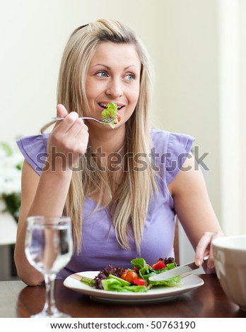 Portrait of a jolly woman eating a salad in a living-room