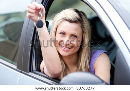 Portrait of an attractive young driver holding a key after buying a new car