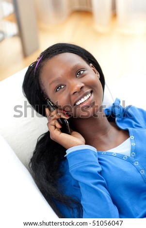 Laughing woman on phone lying on a sofa in the living-room