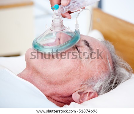 Senior patient receiving oxygen mask lying on a hospital bed