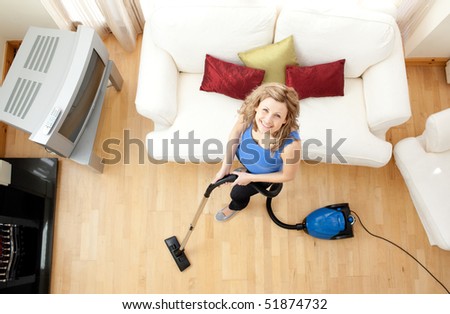 High angle of a mirthful woman vacuuming in the living-room