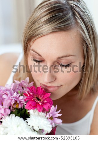 Beautiful woman smelling a bunch of flowers at home
