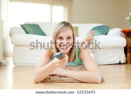 Young woman watching TV lying on the floor at home
