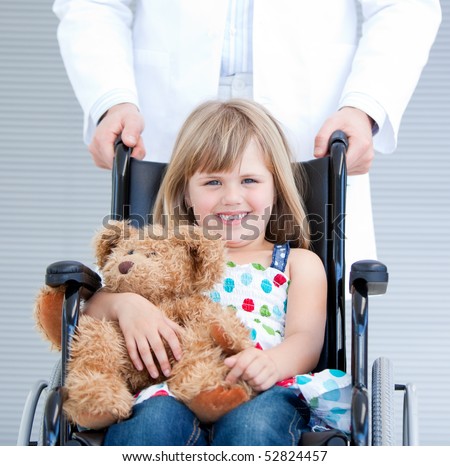 Portrait of a little girl sitting on the wheelchair supported by a male doctor at the hospital
