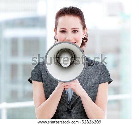 Confident businesswoman yelling through a megaphone standing in the office