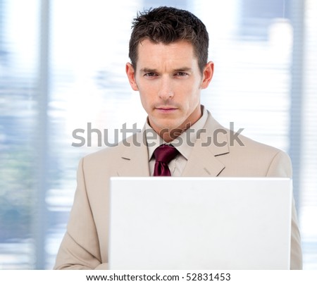 Self-assured businessman using a laptop standing in the office