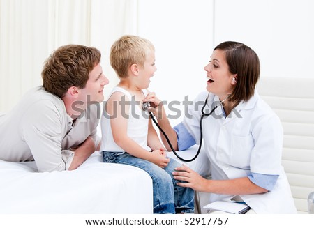 Beautiful female doctor examining a little boy with his father at the hospital