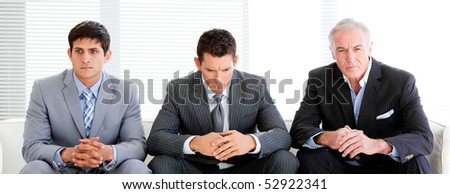 Three charismatic businessmen sitting on a sofa in a waiting room
