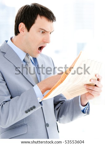 Portrait of a surprised businessman reading a newspaper in the office