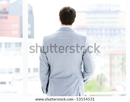 Ambitious businessman looking through a window in the office