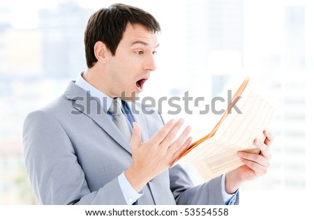 Portrait of a annoyed businessman reading a newspaper in the office
