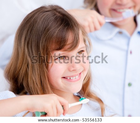 Smiling girl brushing her teeth against a white background