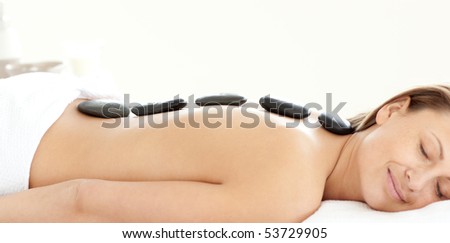 Charming woman with hot stones on her back in a Spa center