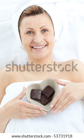 Cheerful woman holding a bowl in the shape of a heart with chocolate in a Spa center